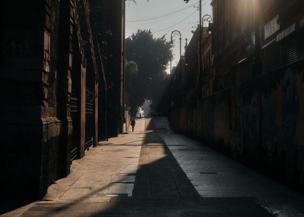 One person in distance walking along empty road in the morning