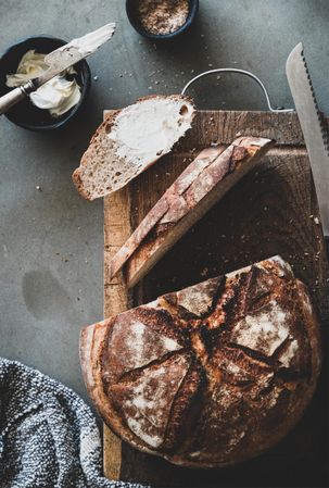 Freshly baked sourdough bread loaf, sliced, vertical composition, with spread butter