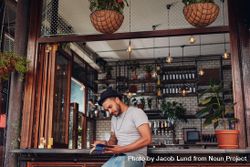 Portrait of relaxed young man sitting at a cafe counter reading a book 0LNPX4