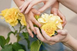 Mother and child holding yellow roses. Background flowers