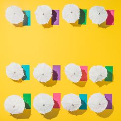 Pattern of sun umbrellas and multicolored towels in rows on yellow