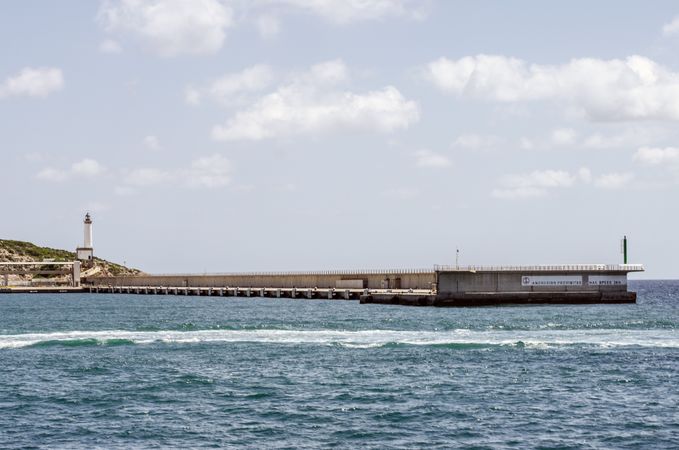 Lighthouse tower near a concrete pier walkway