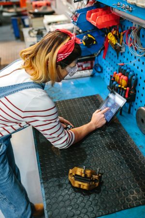 Mechanic woman checking disk brake with diagnosis app in digital tablet
