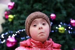 Young girl expressing sadness standing against a decorated tree