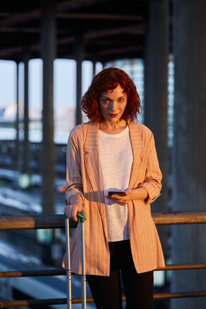 Smiling young woman browsing on phone at station