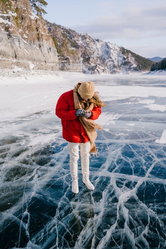 Woman in skates standing on ice and using phone