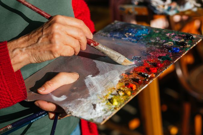 Crop artist with paint palette in workshop