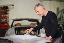 Mechanic grinding paint from car detail