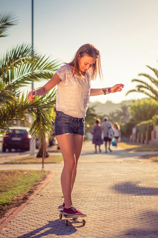 Young girl riding in a skateboard outdoors on summer