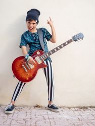 Energetic kid gesturing rock holding guitar