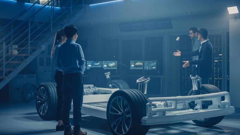 Automobile Engineers Discussing and Designing Electric Car Chassis Platform, Using Tablet Computers with 3D CAD Software.