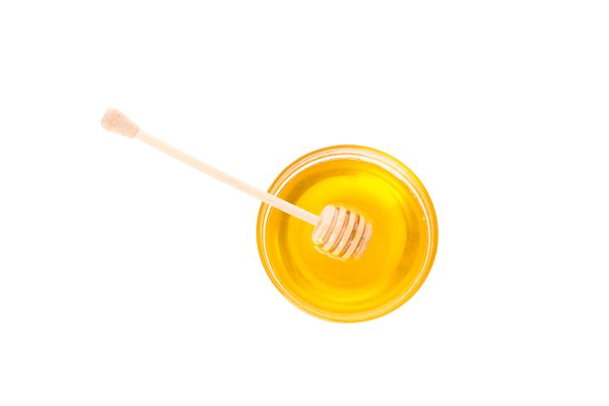 Dipper and honey in glass bowl isolated on plain background