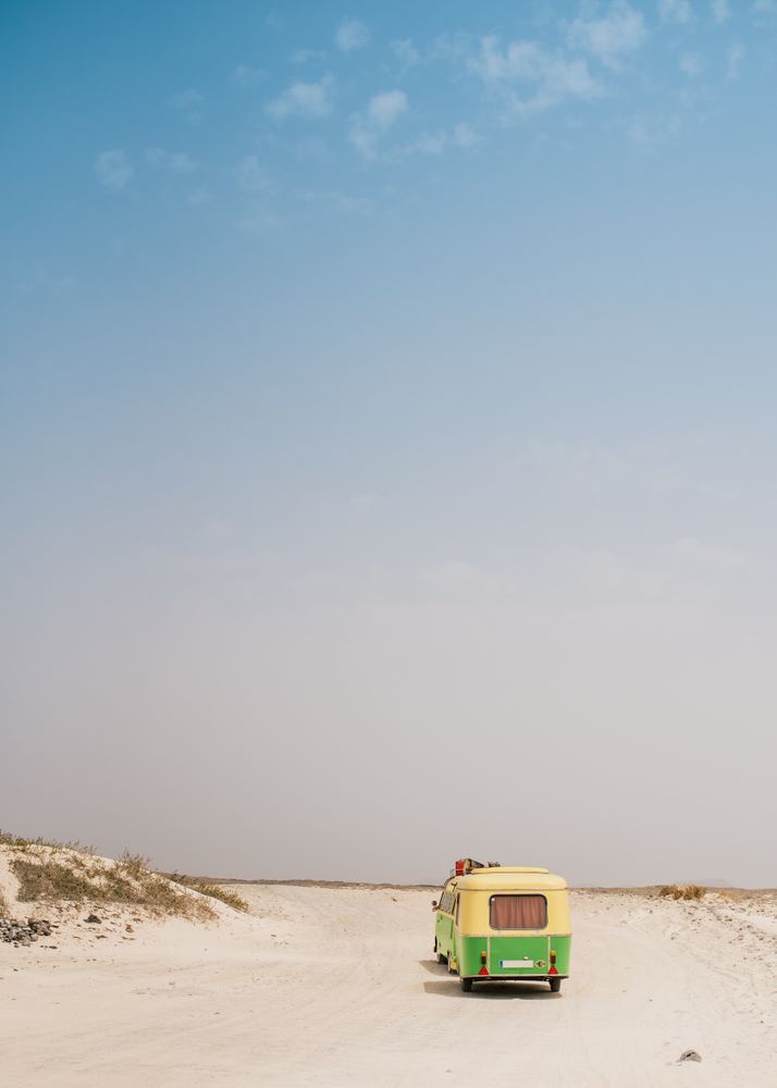 Colorful minibus with trailer parked on sandy shore in sunny day