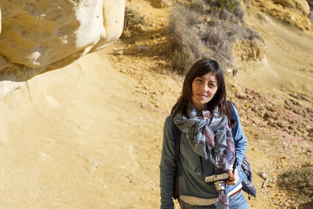 Female with camera standing in rocky and sandy terrain