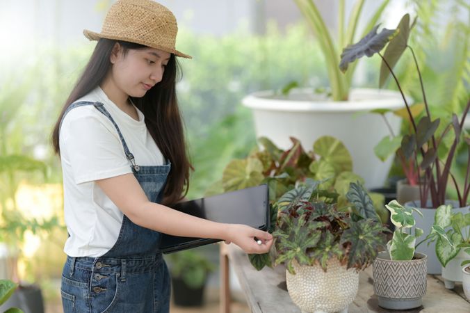 Asian female tending to pots of plants at work