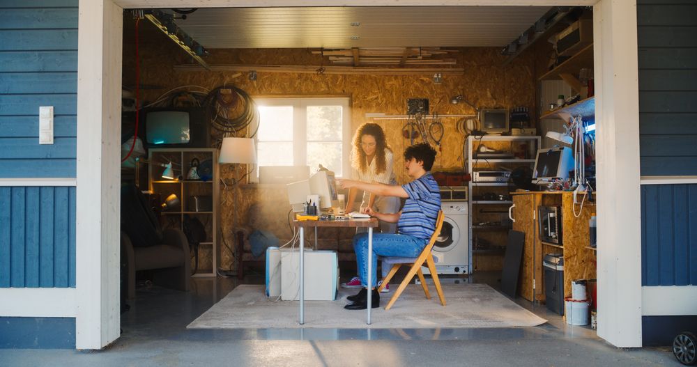 White Male Software Developer And Hispanic Female Designer Talking And Using Old Desktop Computer in Retro Garage.