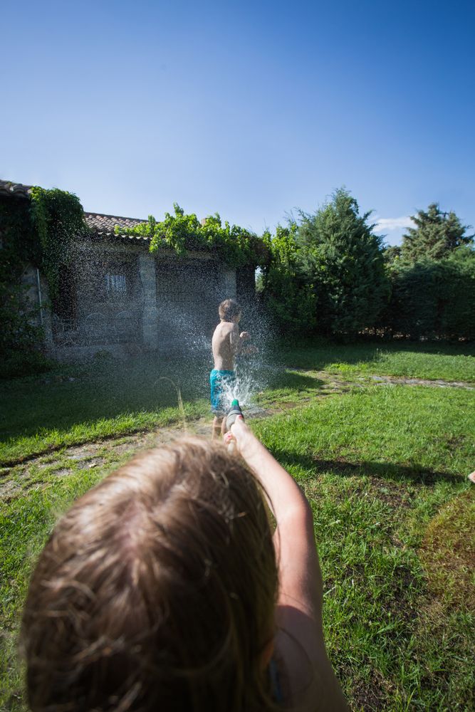 Little kids in swimwear having fun with splashing water