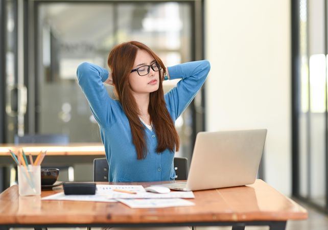 Asian woman wearing glasses with eyes closed to relieve stress from work
