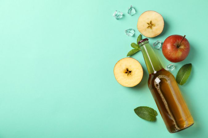 Composition with cider, apples and ice on mint background