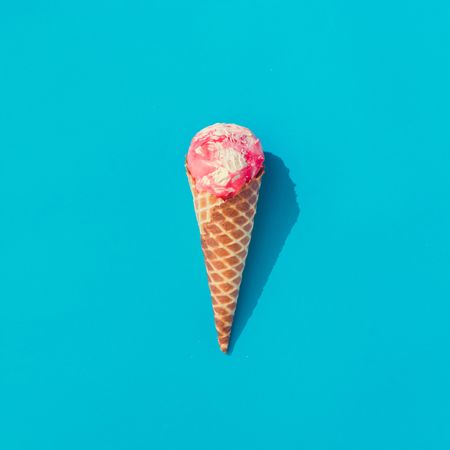 Waffle cone of pink ice cream on bright blue background