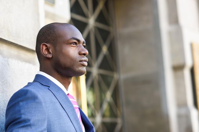 Serious male in business attire standing outside building with copy space