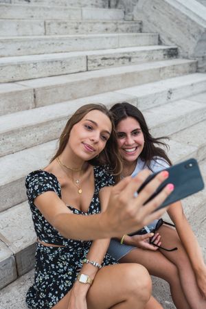 Laughing women taking selfie on stairs at old building