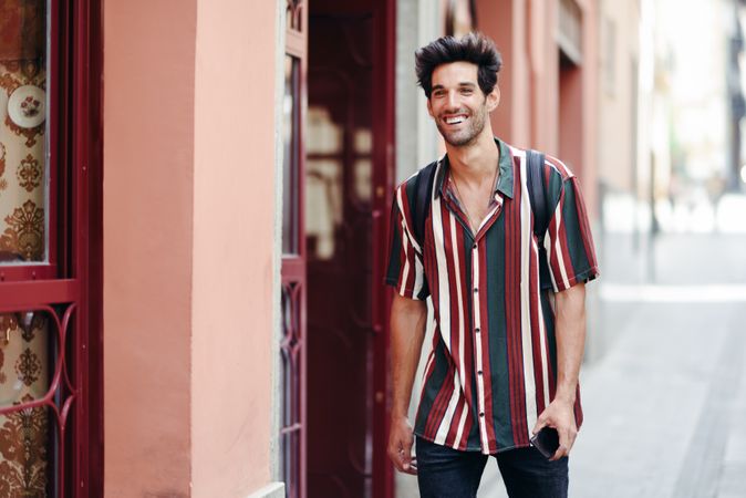 Man with dark hair wearing casual clothes walking down street outside