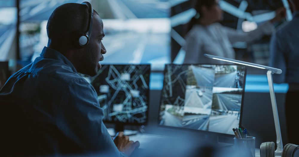 Black Technical Support Manager Using Headphones with Built-In Mic for Communication with Client