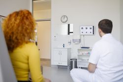 Red haired woman reading eye chart with optometrist
