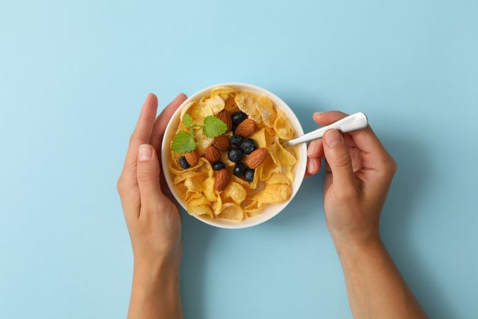 Female hands hold bowl of muesli on blue background
