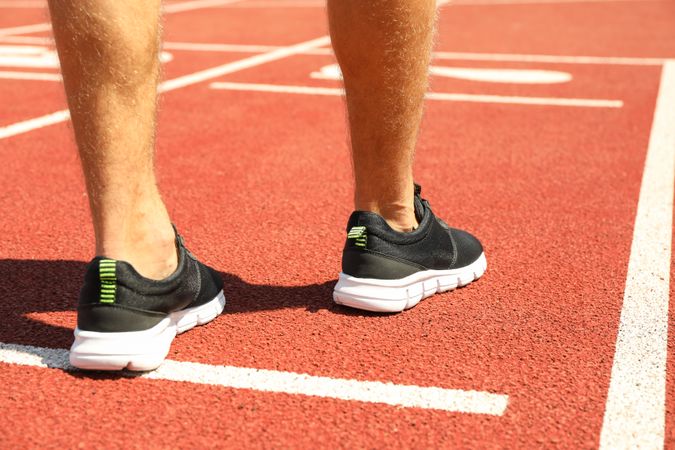 Man in sneakers on red athletic running track, close up