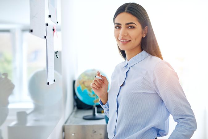 Confident female entrepreneur working off a dry erase board in bright office