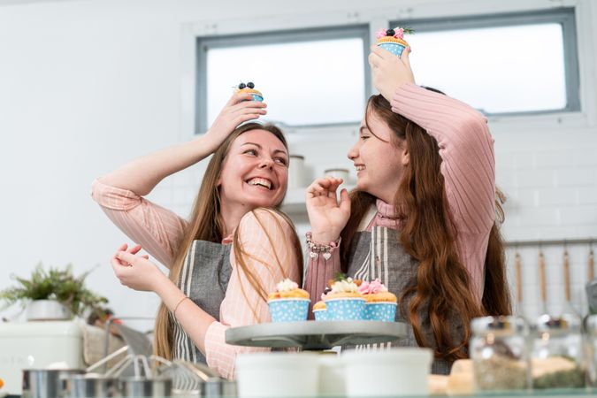 Mother and daughter playing in the kitchen with cupcakes