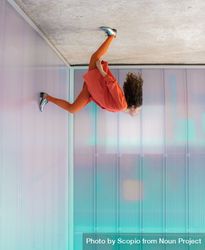 Upside photo of woman in orange casual outfit leaning her head back with one foot on wall 4ZMQr5