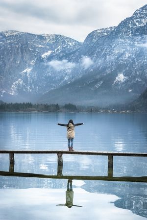 Woman on a bridge enjoying the view of the Alps with arms outstretched
