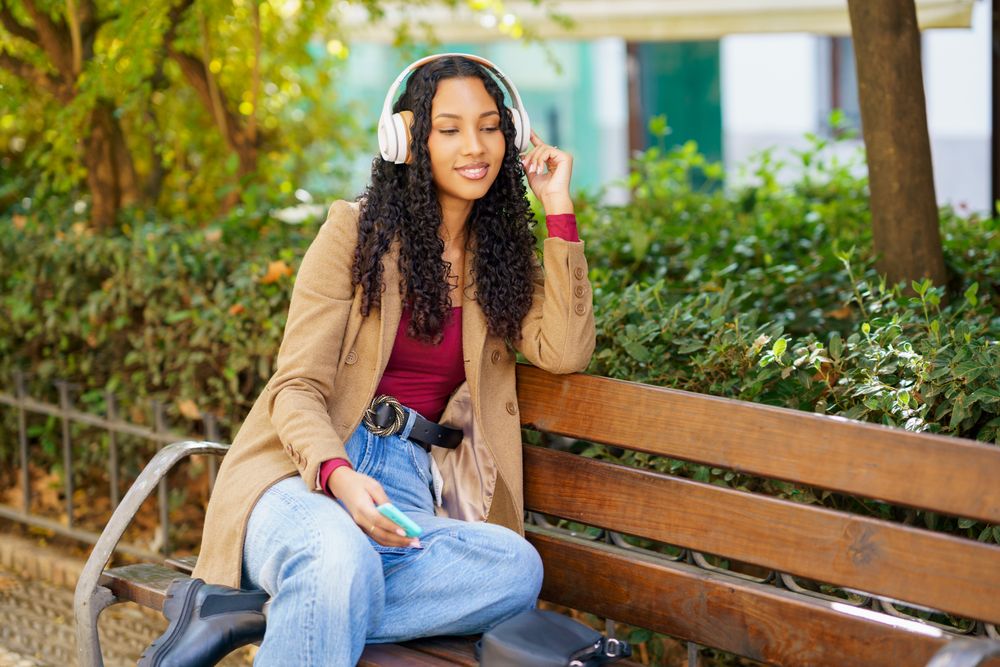 A Young Woman Is Relaxing in the Park While Enjoying Her Music with Headphones On