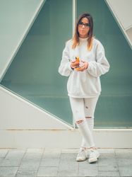 Young woman with headphones standing against wall
