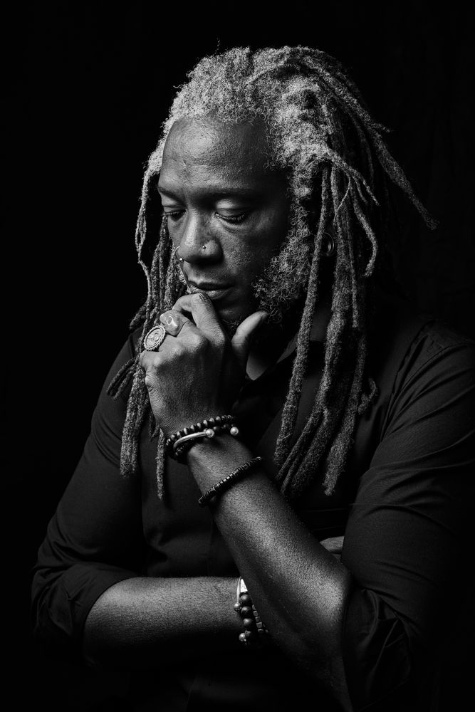 Grayscale photo of man with his hand on chin