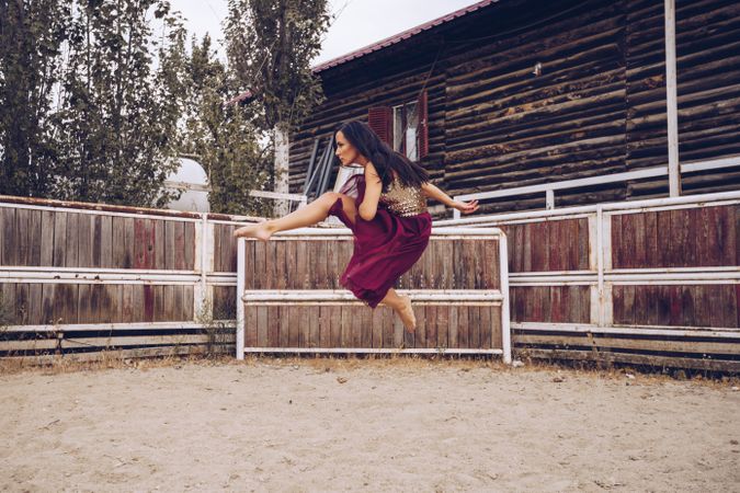 Expressive woman in colorful skirt dancing at rural paddock
