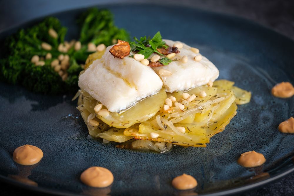 Plate with gratin and fish served with sauce and broccoli