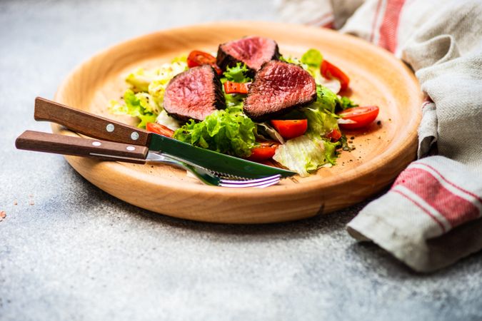 Steak salad with fresh lettuce and tomatoes served with cutlery