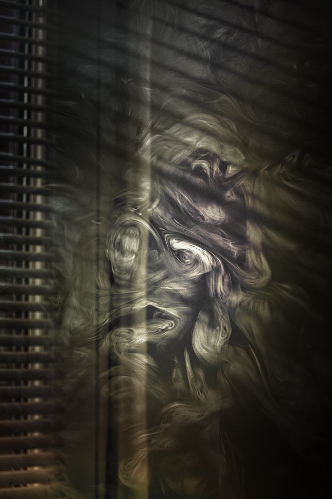 Smoke swirling in dark room with blinds
