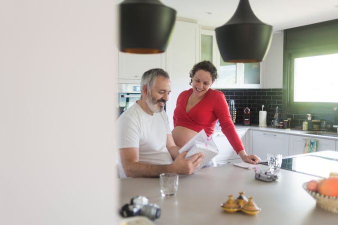 Smiling couple consulting a book at the kitchen