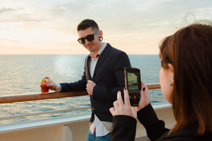 Woman taking photo of man on deck of ship at sea