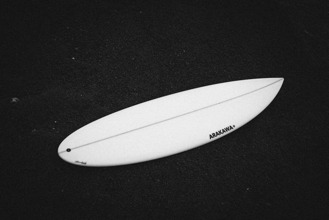 Surfboard lying on dark sand