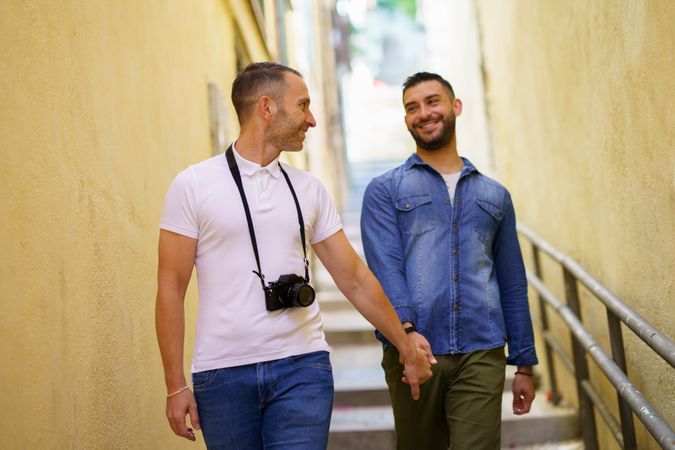 Male couple walking down stairs while holding hands