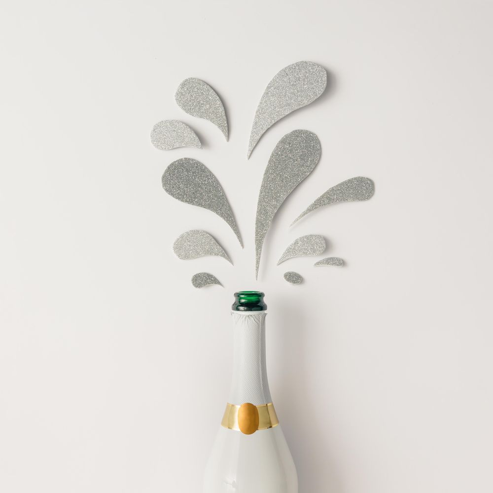 Champagne bottle with silver glittering splashes on light background