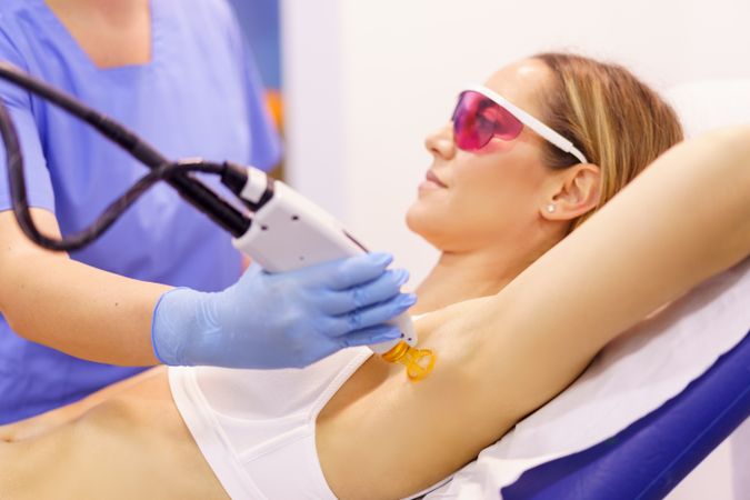 Client in protective glasses having laser hair removal treatment at clinic
