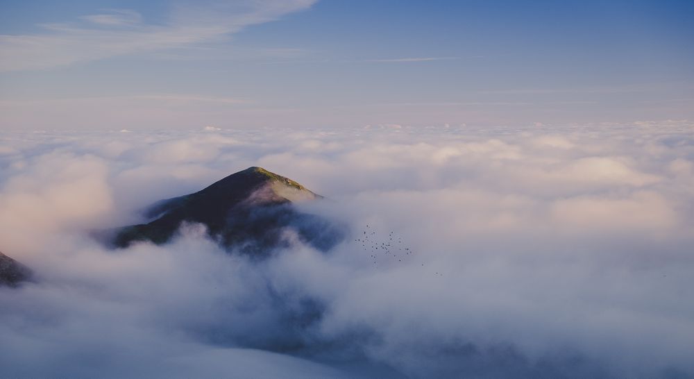 Wonderful view of blue sky above thick clouds in valley from mountain