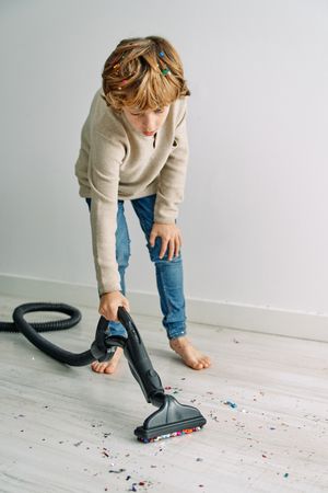 Boy collecting confetti with vacuum cleaner